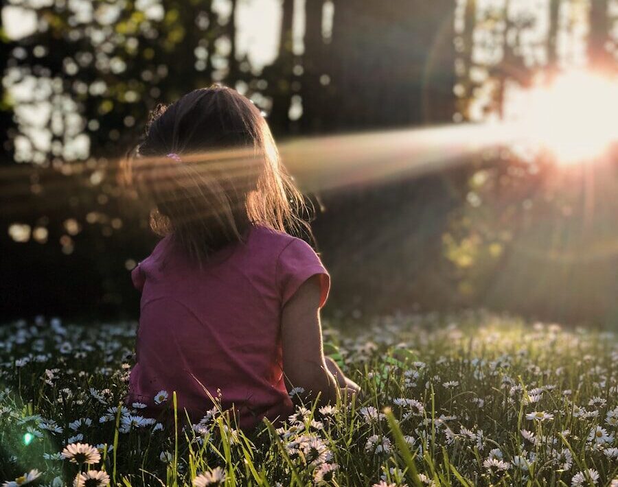 girl sitting on daisy flowerbed in forest